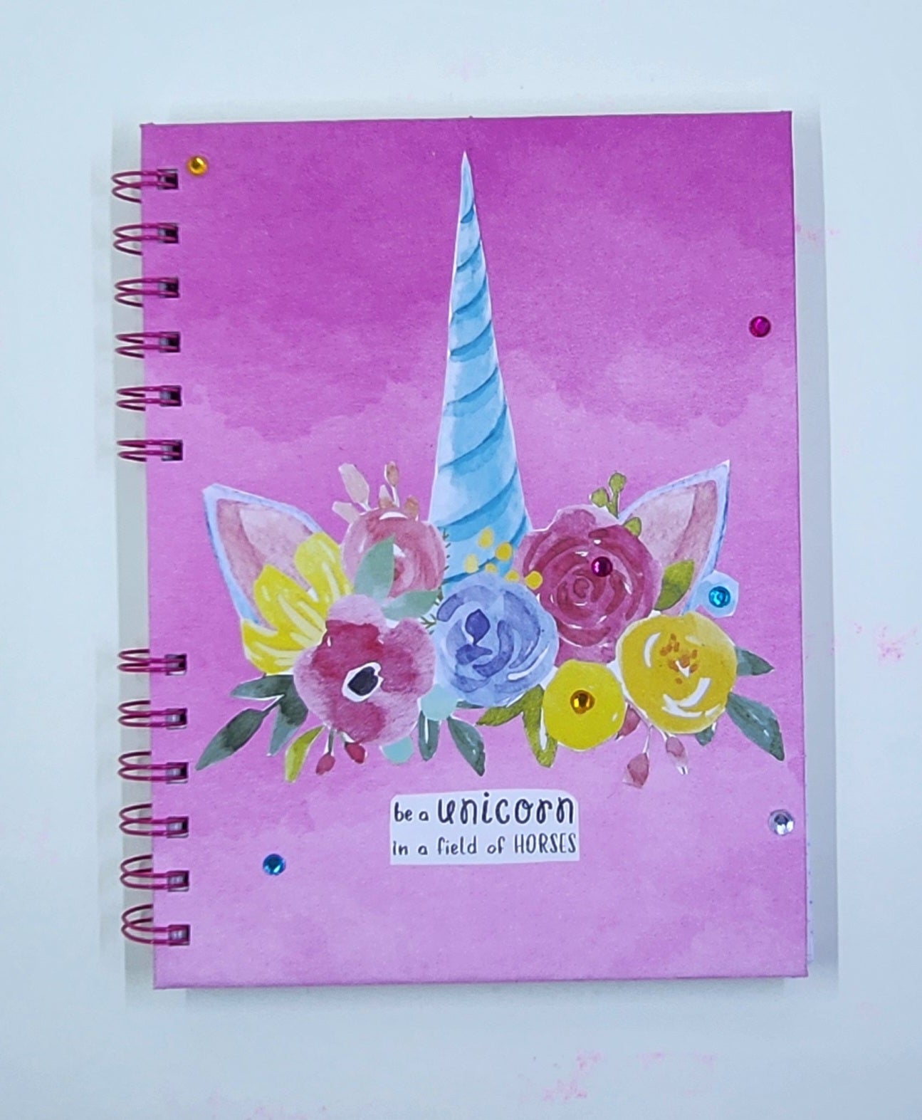 Notebook with unicorn and floral design on a pink background