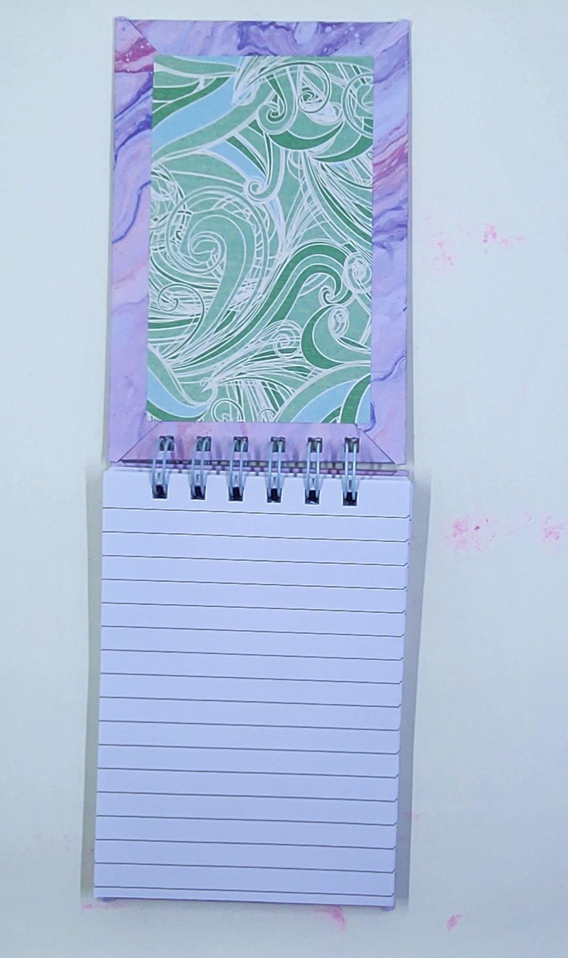 Notepad with a decorative purple and green inside cover on a white background