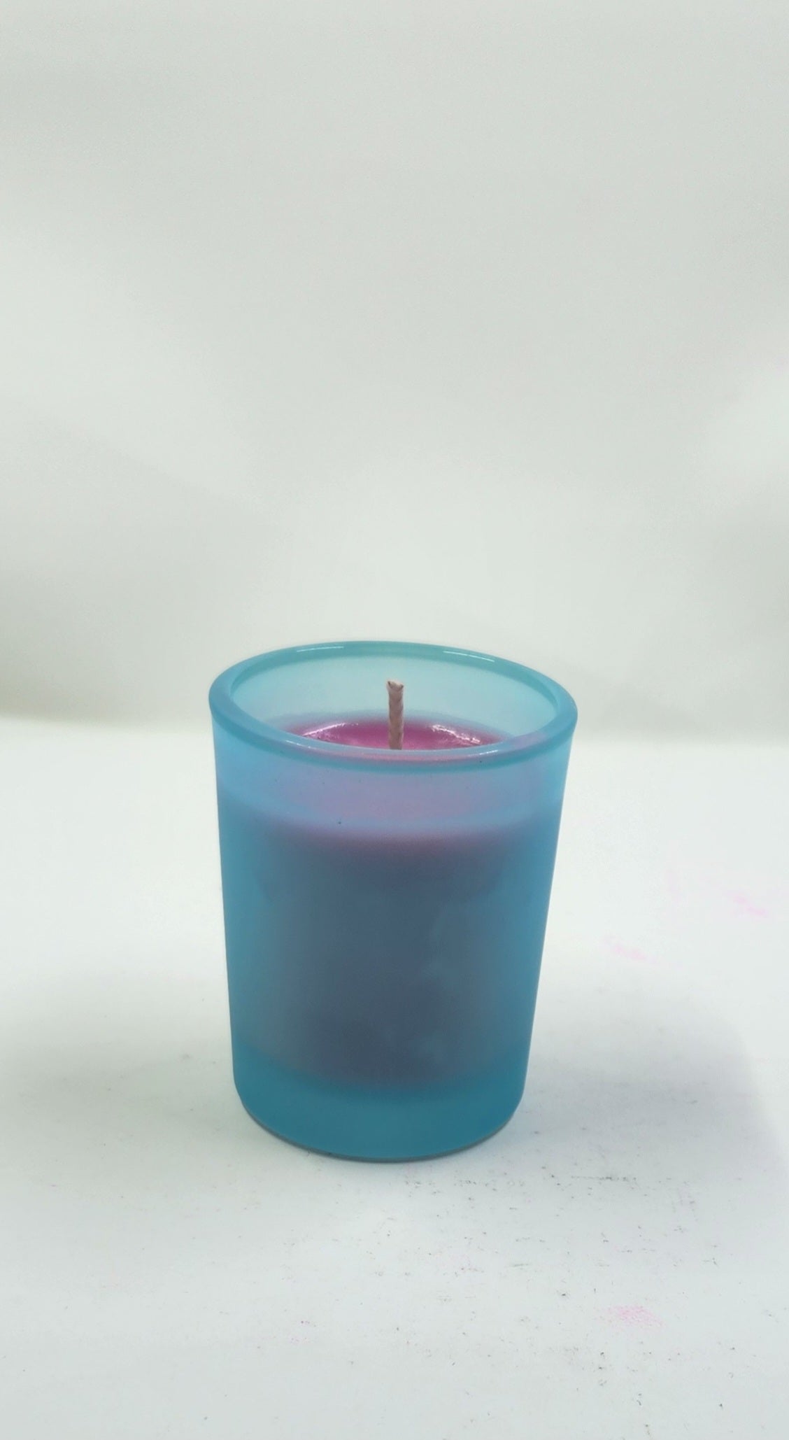 Blue candle in a glass holder on a white background