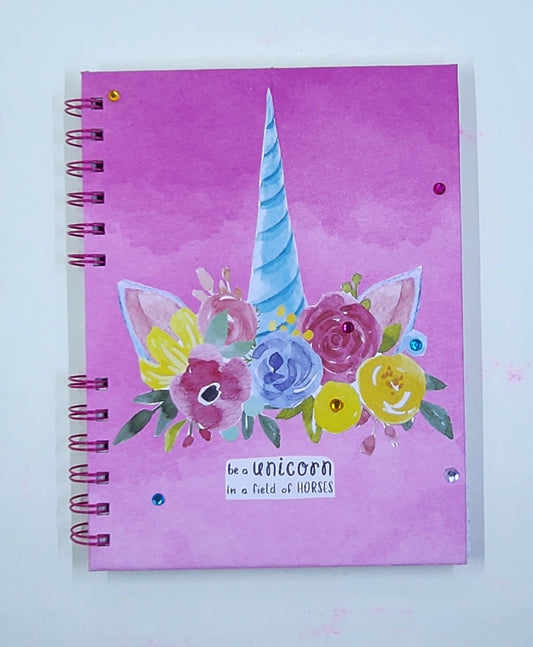 Notebook with unicorn and floral design on a pink background