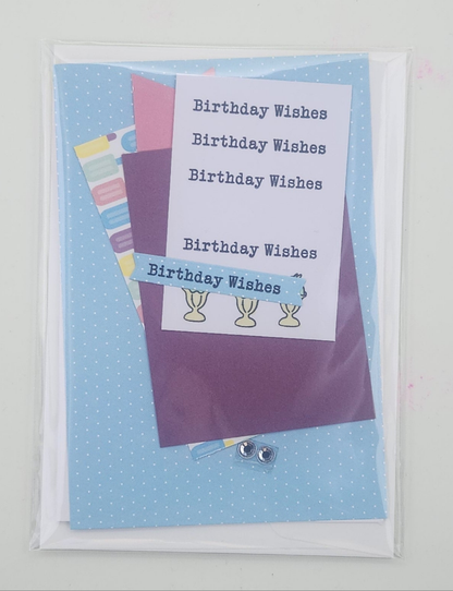 Greeting card with 'Birthday Wishes' text and colorful paper pieces on a blue polka dot background.