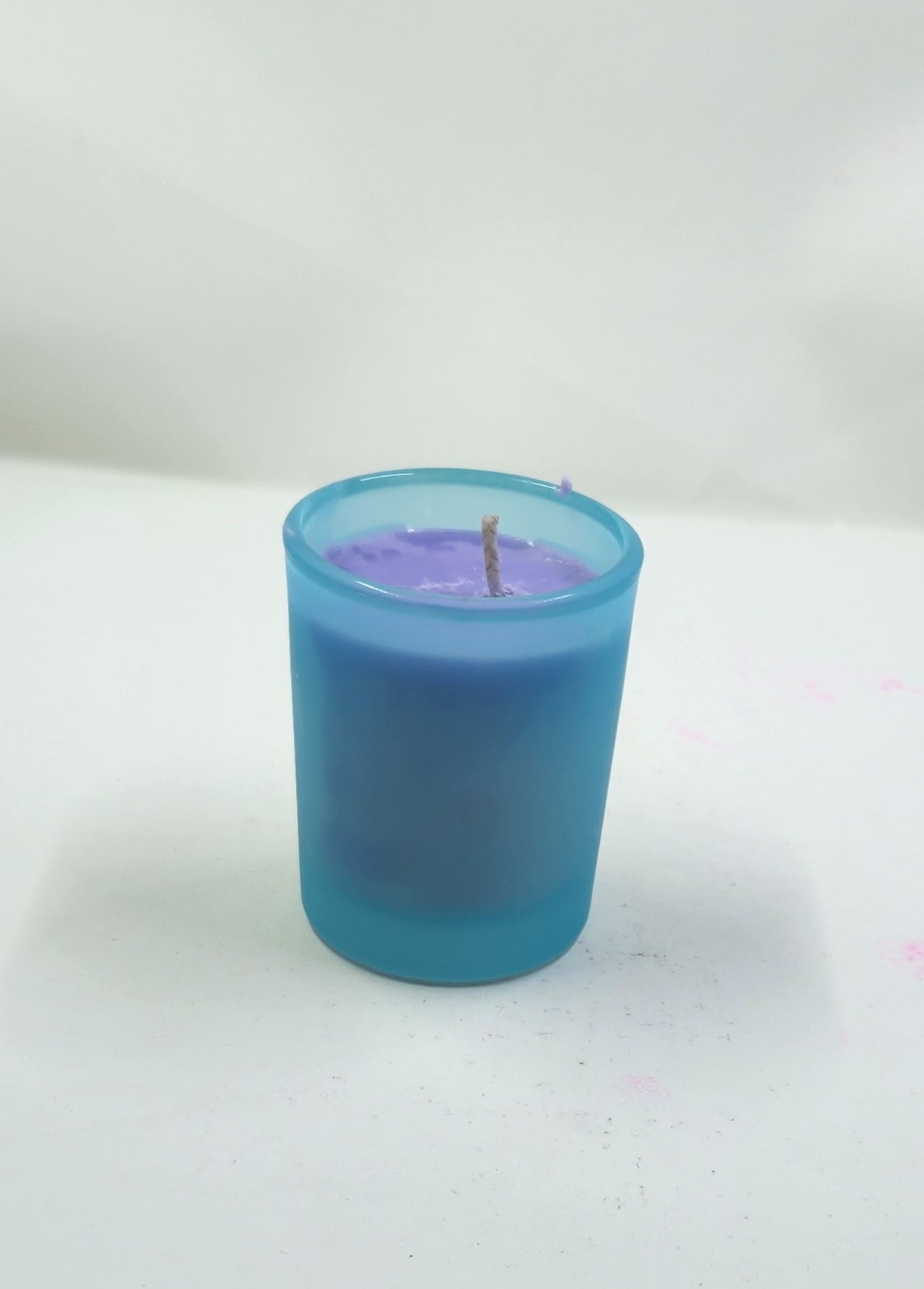 Blue candle with purple wax on a white background