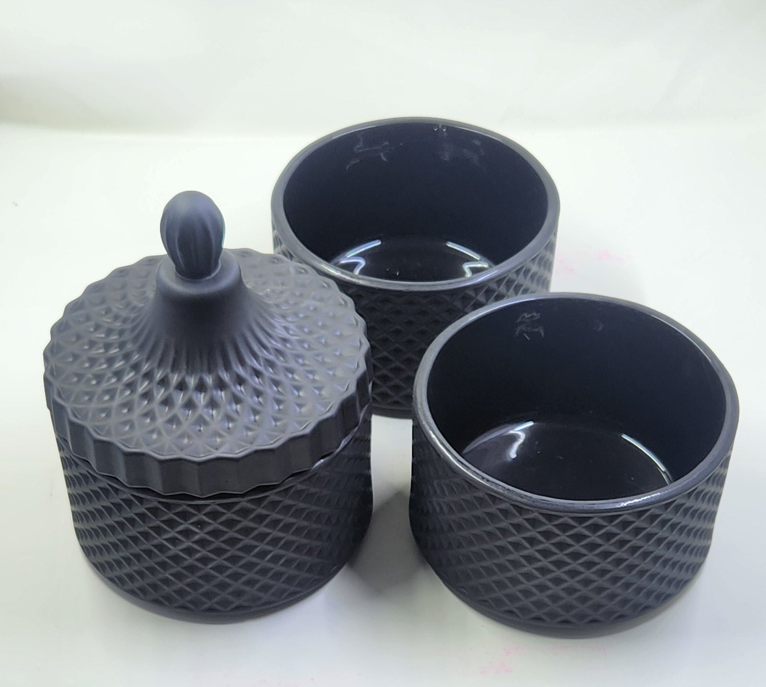 Three black textured containers with a lid on a white background