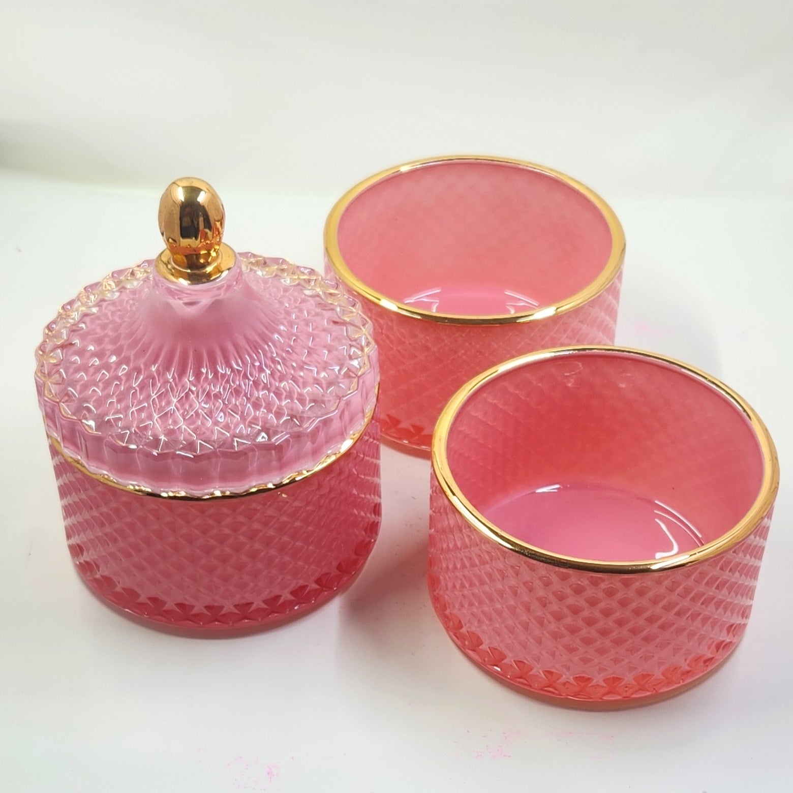 Set of pink glass containers with gold rims on a white background