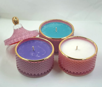 Three scented candles in decorative holders on a white background