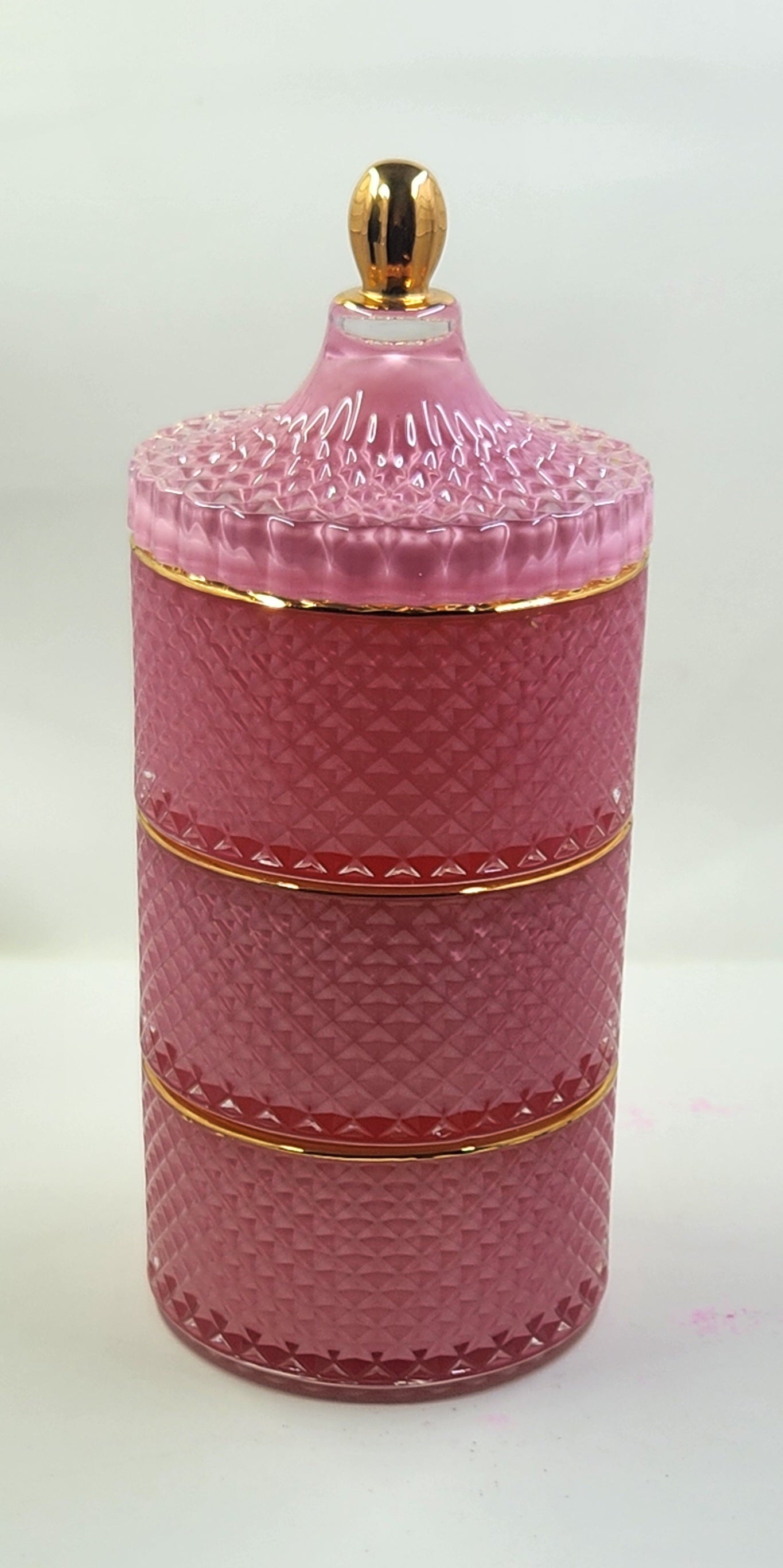 Pink ceramic jar with gold accents on a white background