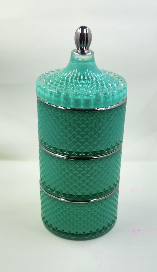Turquoise glass jar with textured design and silver accents on a white background