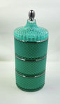 Turquoise glass jar with textured design and silver accents on a white background