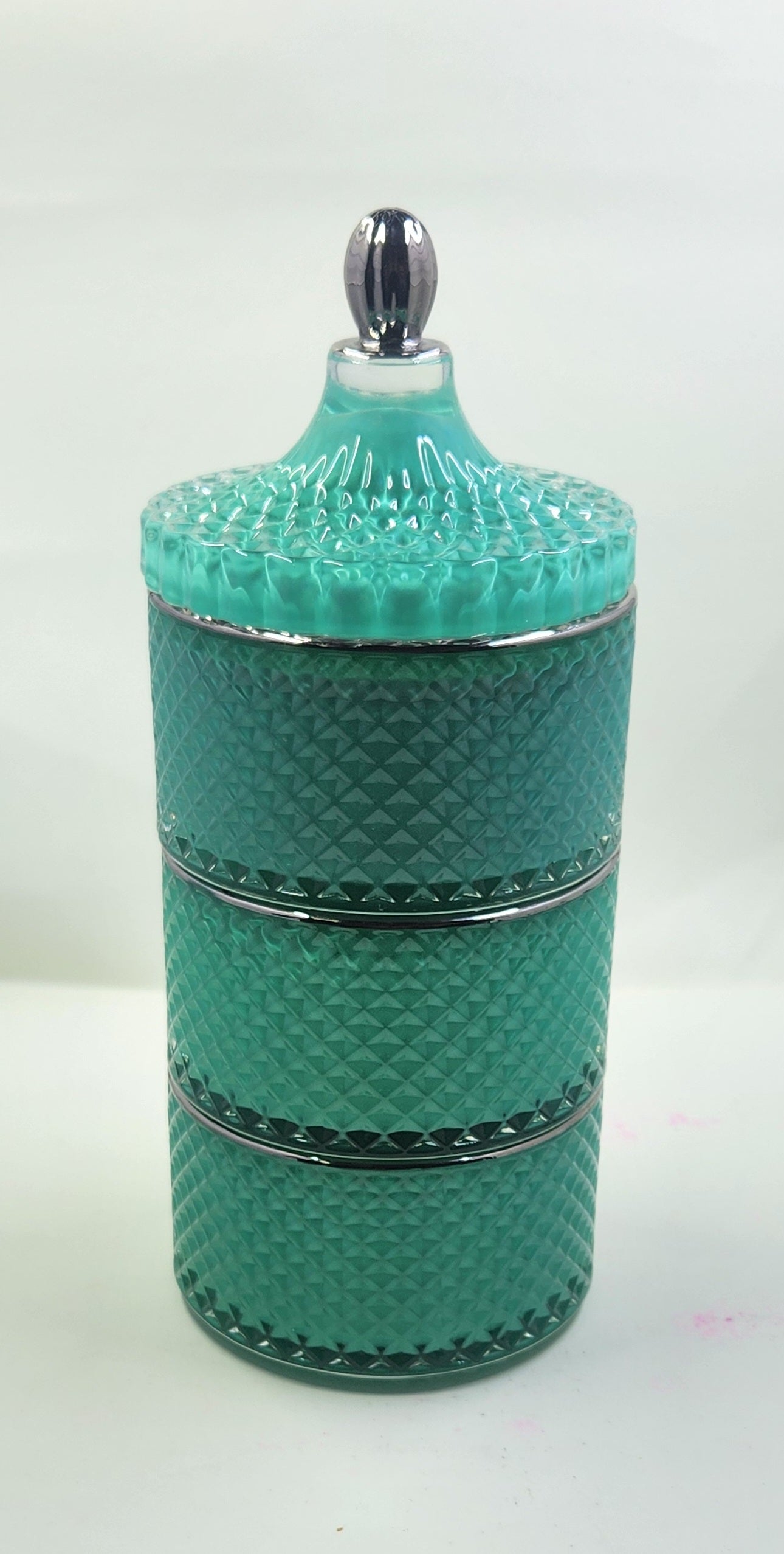 Teal textured jar with silver accents on a white background