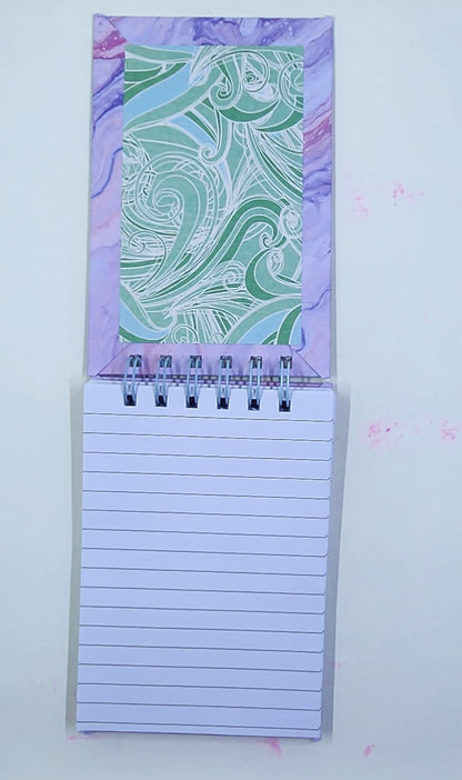 Notepad with a decorative purple and green inside cover on a white background