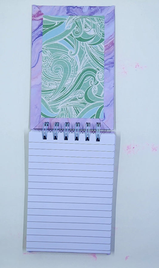 Notepad with a decorative purple and green inside cover on a white background