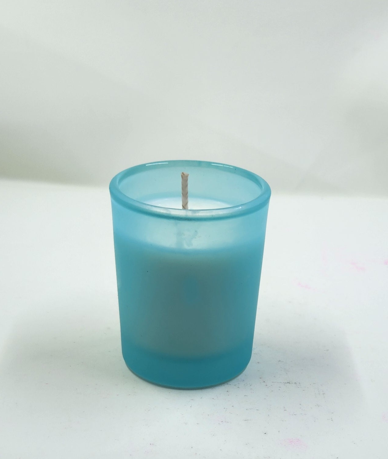 White candle in a blue glass holder on a white background