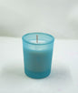 White candle in a blue glass holder on a white background