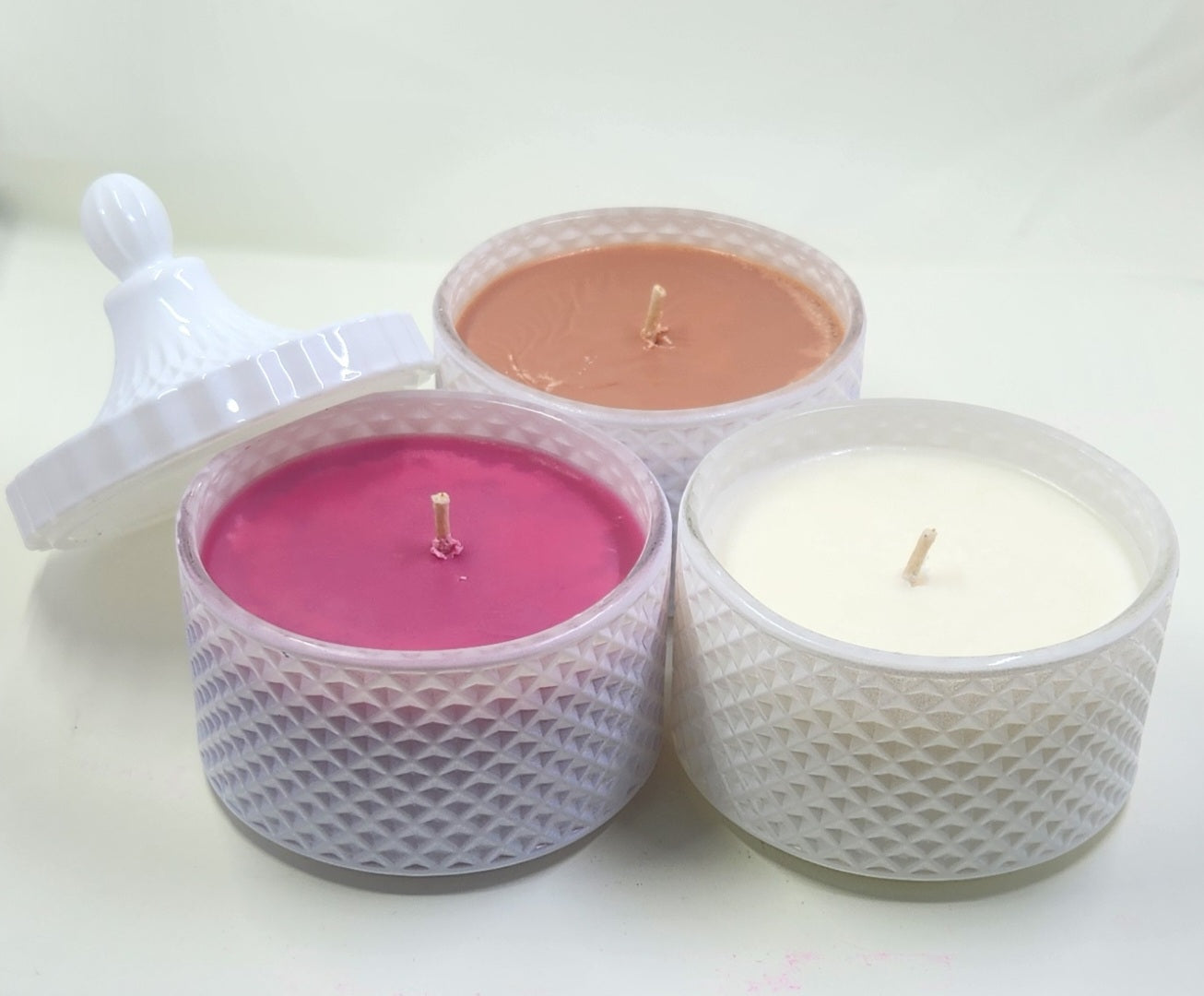 Three scented candles in mesh-wrapped containers on a white background